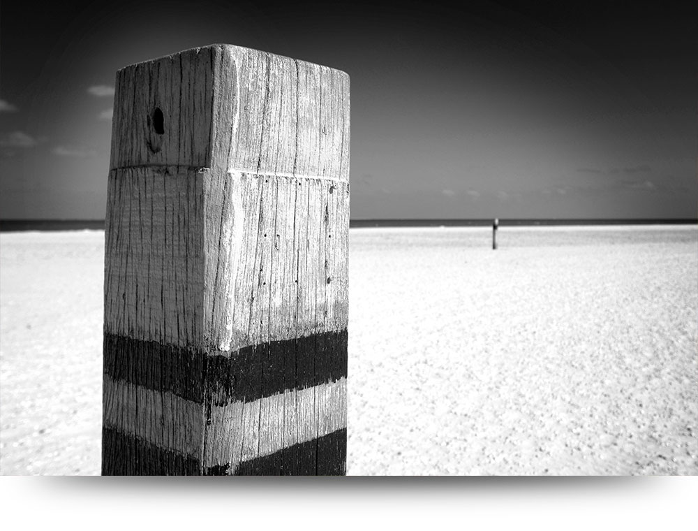 Strandpaal in zwart-wit - Acrylglas schilderij 120 x 80 cm
